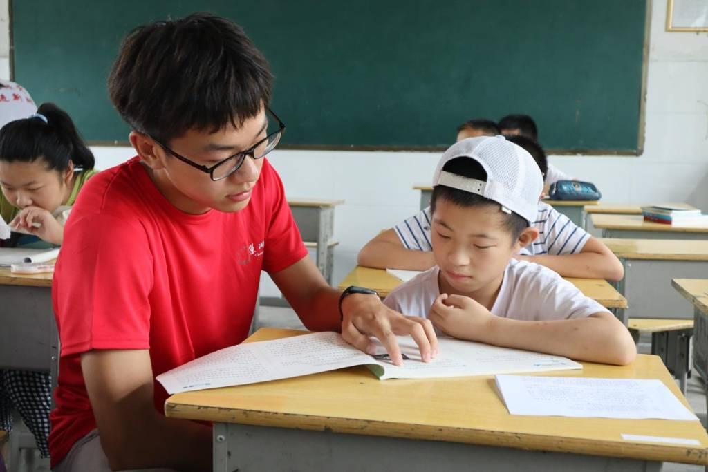 图为志愿者对小朋友进行作业辅导。你求知若渴的眼神，为我的支教生活增添了一抹暖意。