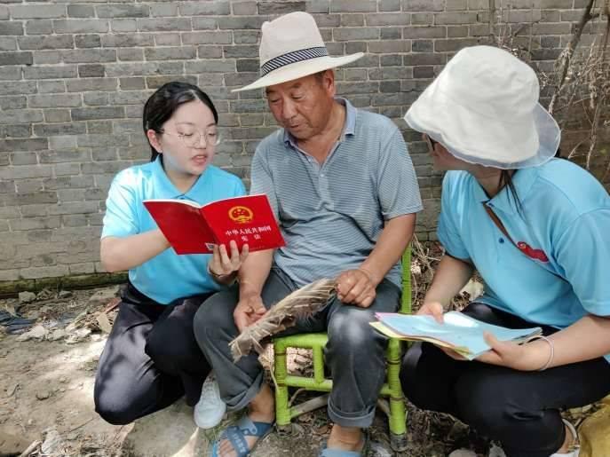 图为服务队成员在给一位老人讲解宪法宣传小册子，老人听得十分认真。