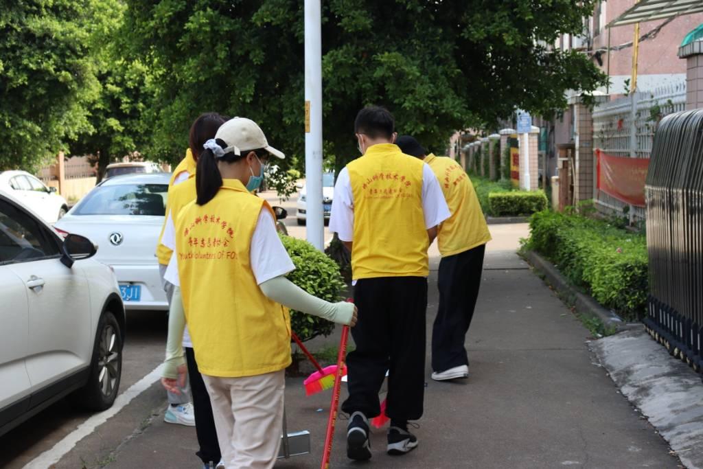 ﻿图为队员拿着扫把、铲子和垃圾袋在街道上准备进行清扫活动。