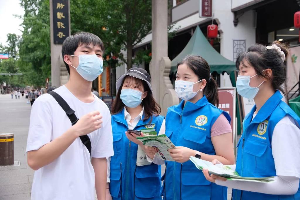 图片为南师学生志愿者在夫子庙景区采访游客。