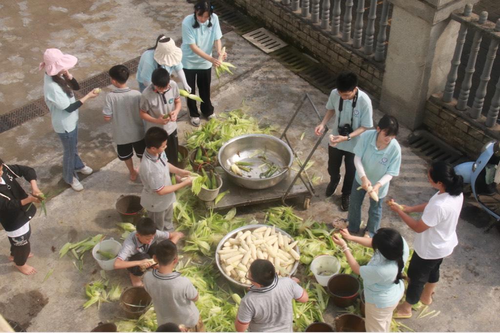 同学们和老师们一起剥玉米。