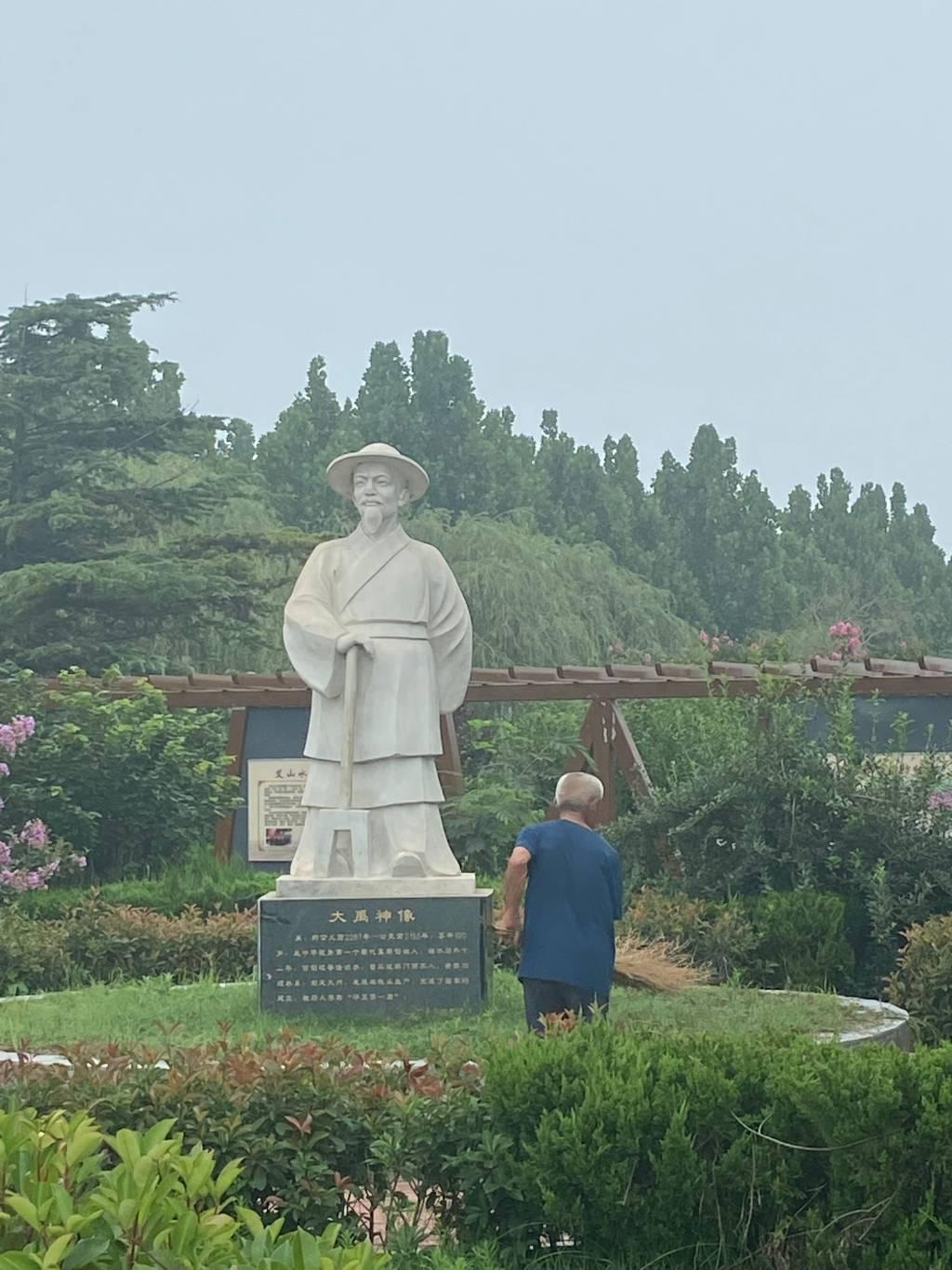 老人在清理大禹雕像旁边的垃圾