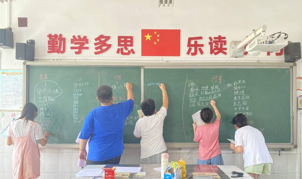 图为同学们在黑板上书写自己所知道的家乡美食、习俗、风景。