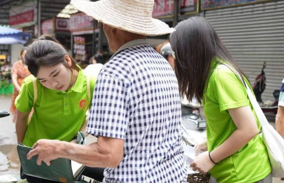 图为卖草药的老人向实践队队员展示他留下来的老医书。通讯员 梁铭聪 摄