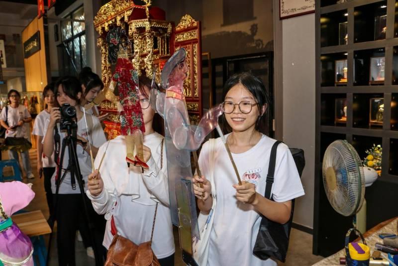 图为实践队队员体验皮影戏表演，感受牛皮、塑料板等不同材质皮影的操作质感。