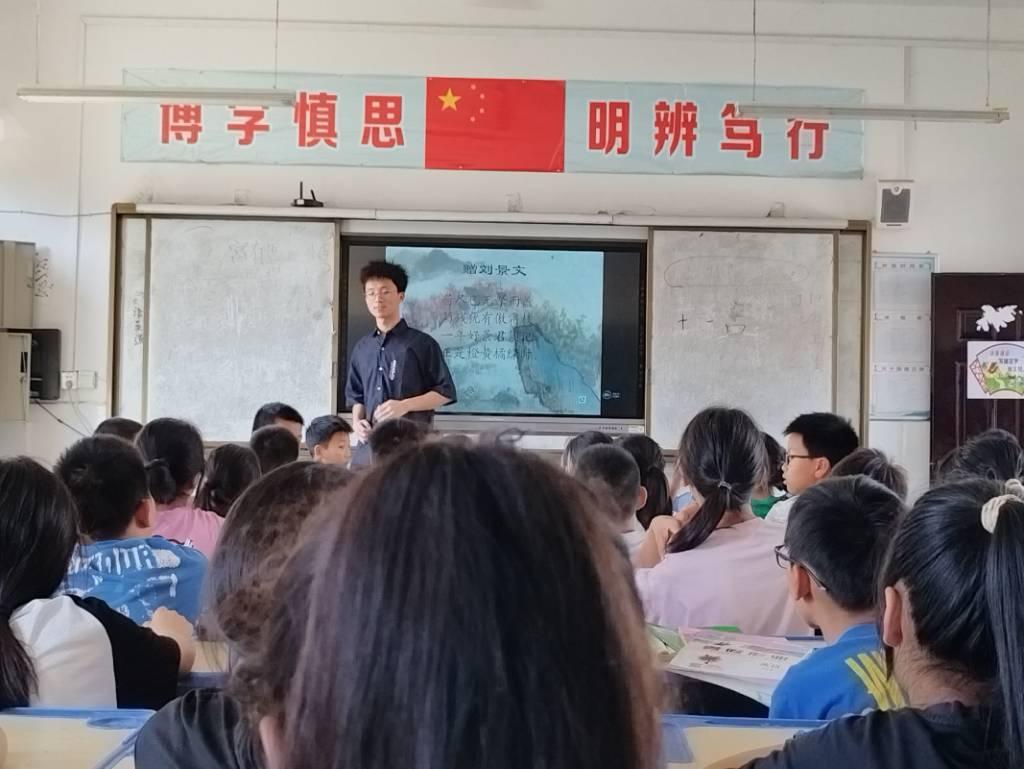 图为志愿者为同学们上古诗朗诵课。古诗是中华传统文化的重要组成部分，通过学习古诗，可以让小学生对中华文化有更深入的了解，增加文化自信心。朗诵古诗要求小学生掌握正确的发音、语调和节奏，通过反复朗读，可以提高他们的语言表达能力，使他们的口语更加流利、准确。古诗以其优美的语言和深刻的意境吸引着人们，通过学习古诗，可以培养小学生对美的感知能力，提高他们的审美情趣。古诗中蕴含着丰富的情感和人生智慧，通过朗诵古诗，可以帮助小学生感受到其中的情感和品德教育，培养他们的情感世界和品德修养。这些都对小学生的全面发展有着积极的影响。