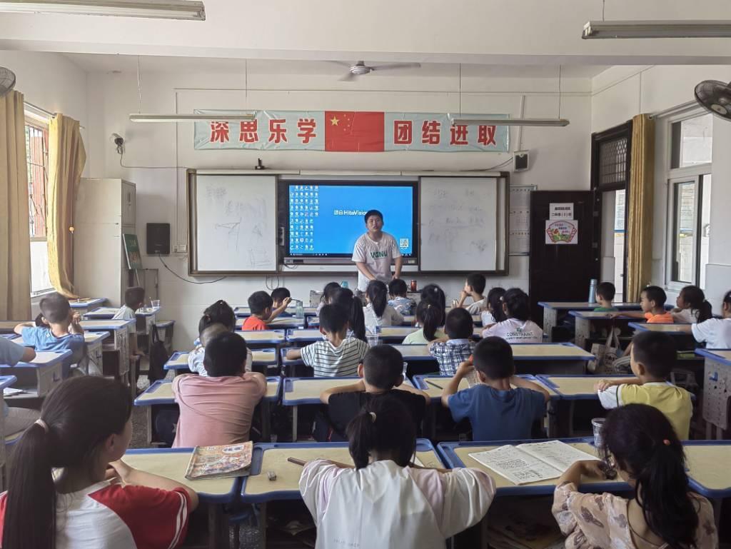 图为志愿者为同学们介绍啦啦操的要领。