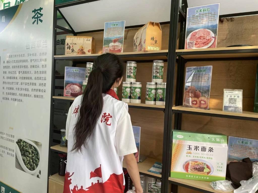 图为蚌埠学院学子了解王畈村的特色农产品。包括锅巴，茶文化，葡萄酒，玉米面条，荞麦面条等等。王畈村合理利用合适的地理位置和适宜的气候，种植茶叶和葡萄。其中岳西翠兰最为有名，清爽回甘，深受购买者等我喜爱。特色产品中，大米锅巴尤其多，是当地最为常见的食物，也颇受游客的喜爱。他们利用自媒体途径直播带货把大别山里的产品带出去，走向全世界。