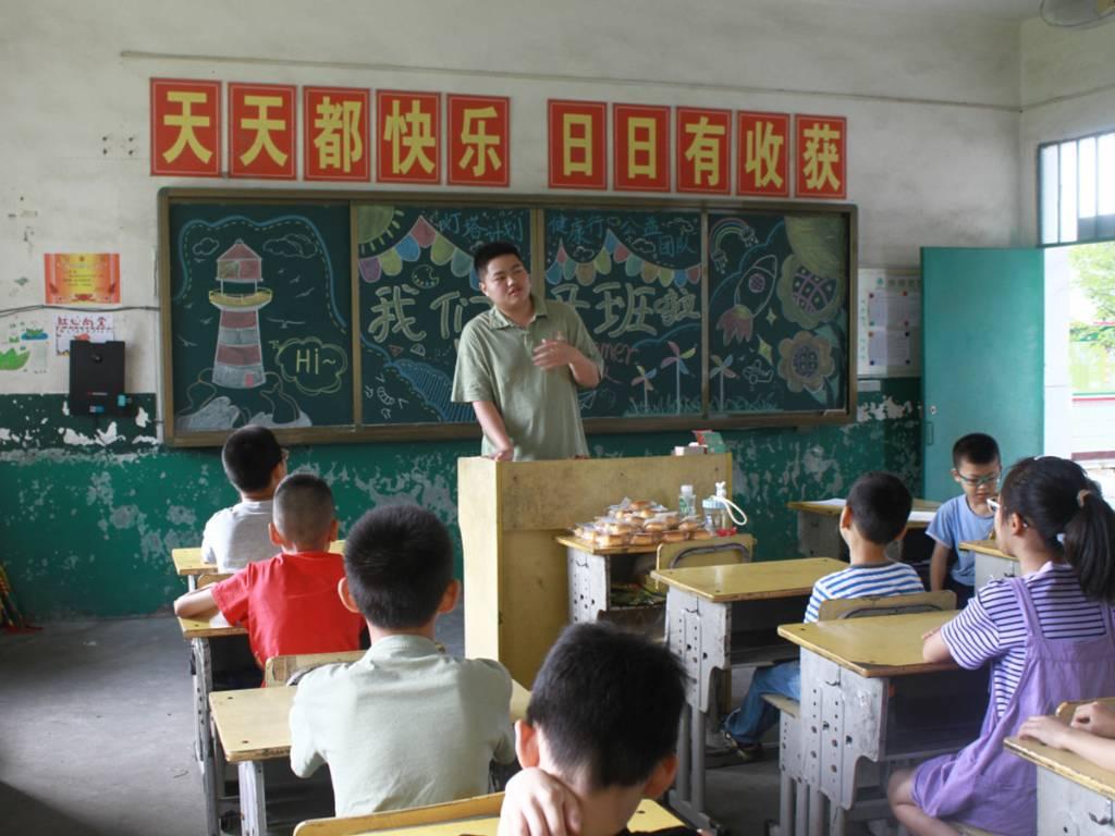 图为志愿者吴干鸣为学生做趣味自我介绍。