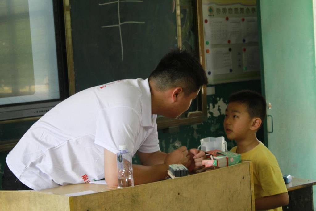 图为志愿者吴干鸣聆听学生关于电视地声音是如何发出来的疑问并解答