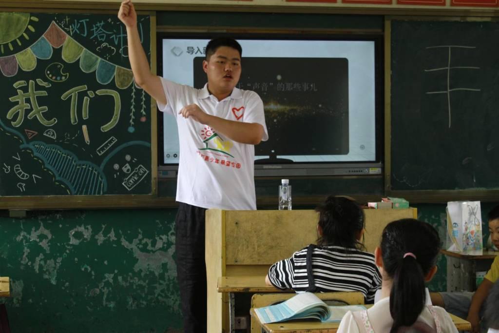 图为志愿者吴干鸣为孩子门演绎天线的原理所做出的动作并一步一步讲解