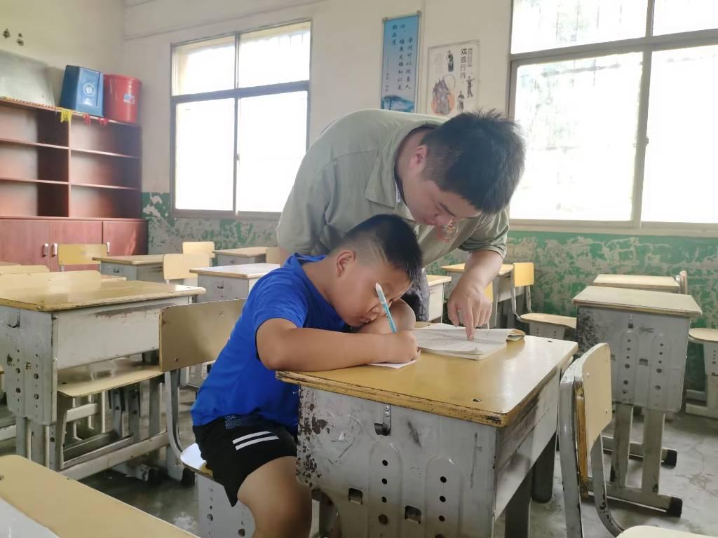 图为志愿者吴干鸣在指导同学们写自己的书籍读后感