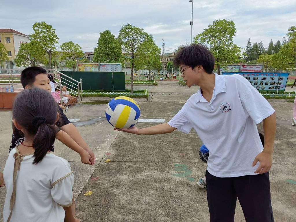 图为排球课上实践队员亲自指导学生动作，让接触排球不多的学生也学会了基本的打排球的技能。