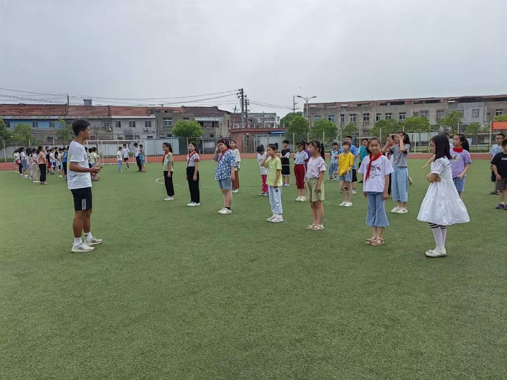 图为足球课上实践队员指导学生动作，用先讲解后练习的方式进行学习。