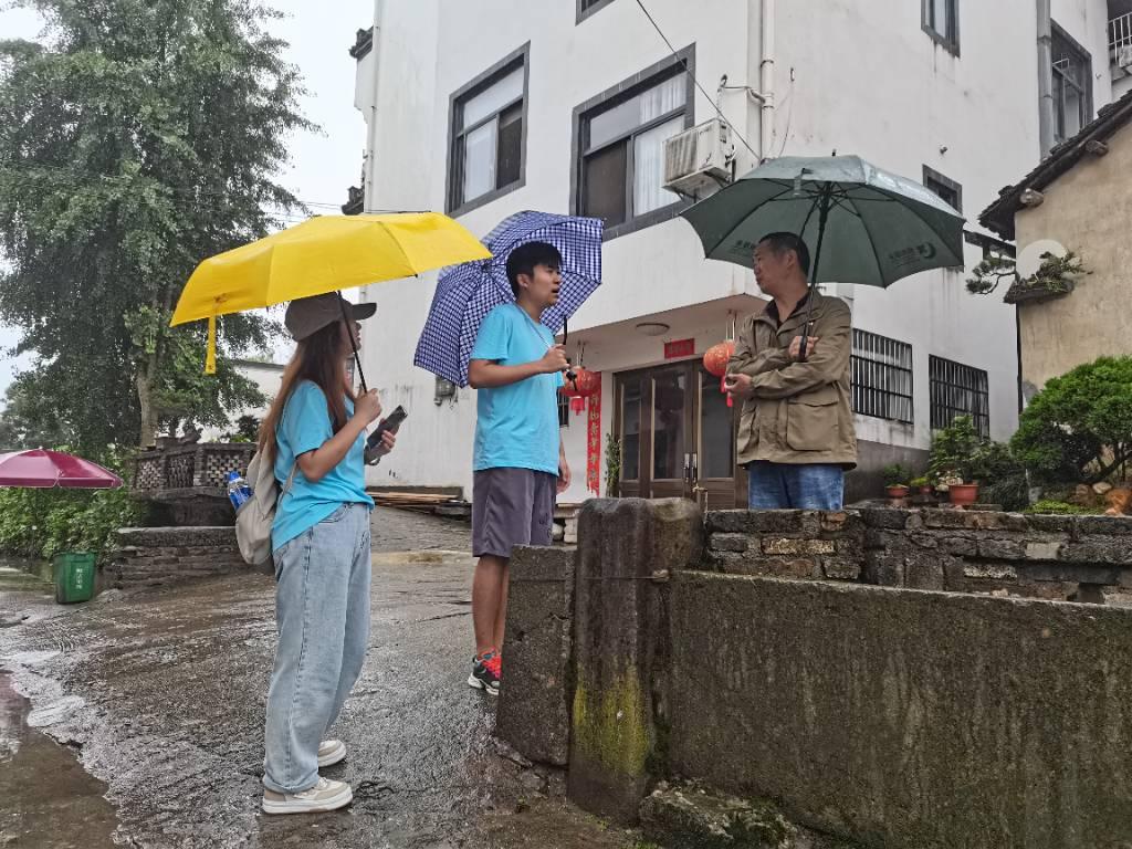 团队成员在黄山市徽州区西溪南村采访当地住户，询问当地古民居的保护和利用情况。