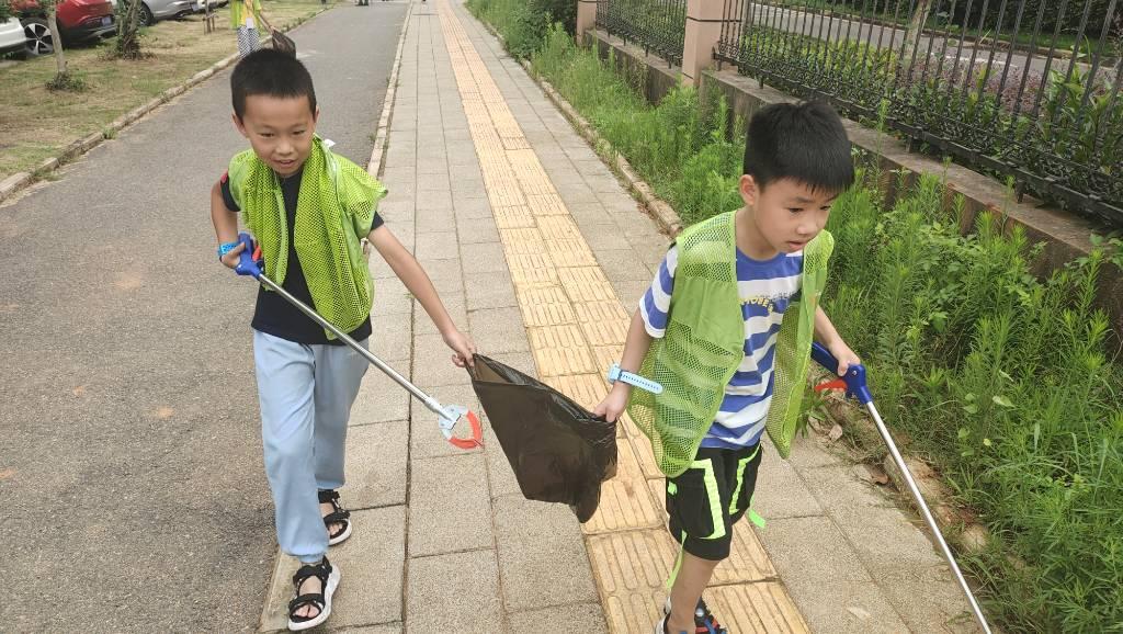 图为孩子们正在寻找路面上的垃圾，他们脸上的笑容表现出他们的的积极。大学生网通讯员 李志扬 摄