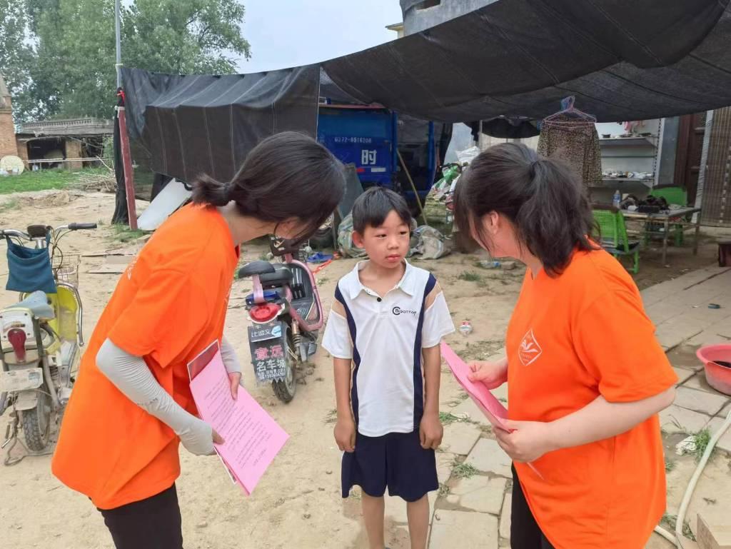 图为实践队员热情地询问男孩在学校中遇到学习和一些其他困难，并积极给出建议。大学生网报通讯员 孔君芳 摄