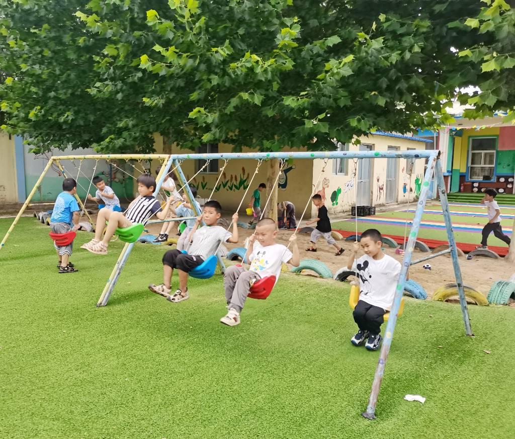 图为雨过天晴后，孩子们在户外场地上快乐地荡秋千。史薇荷 摄