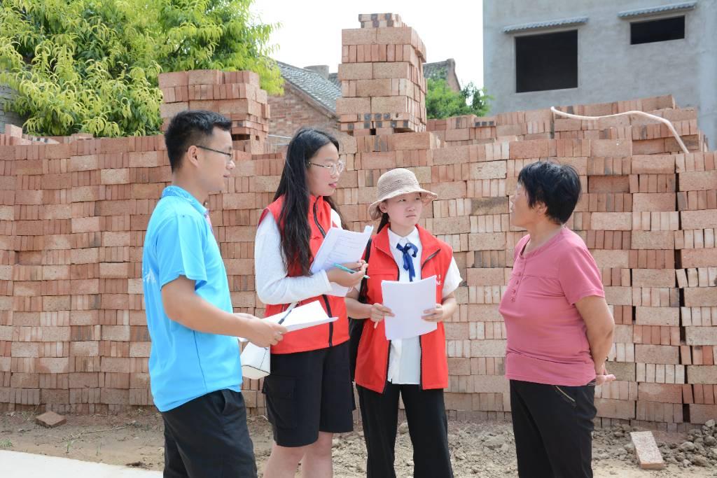 图为当地居民向实践队员询问禁毒防艾相关问题，实践队员认真倾听并做出详细回答。大学生网报网通讯员董德颖供图。