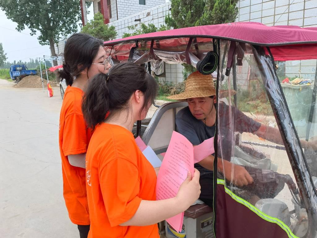 图为实践队员对路过的村民进行分发禁毒防艾知识宣传单。大学生网报通讯员 韩罡 提供