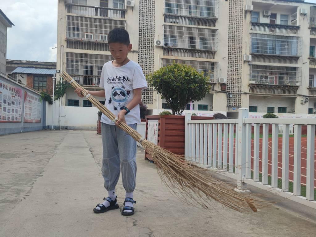 图为班级同学在认真按照支教队员的要求对校园周围的道路进行清扫，打扫干净落叶和垃圾。通讯员 景思溢 供图