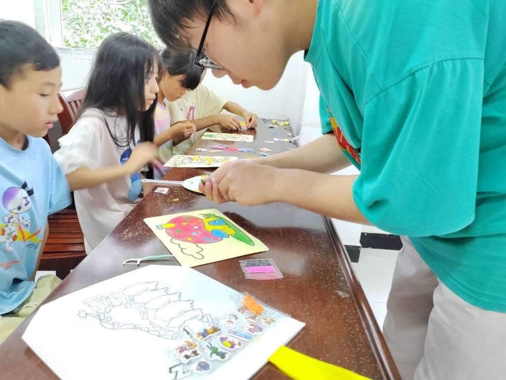 图为实践队员辅导当地孩子学习画沙画。当地留守儿童知识认知匮乏，对外面的世界了解太少，实践队助力孩子们走向未来。中国青年网通讯员 肖鹿敏 供图