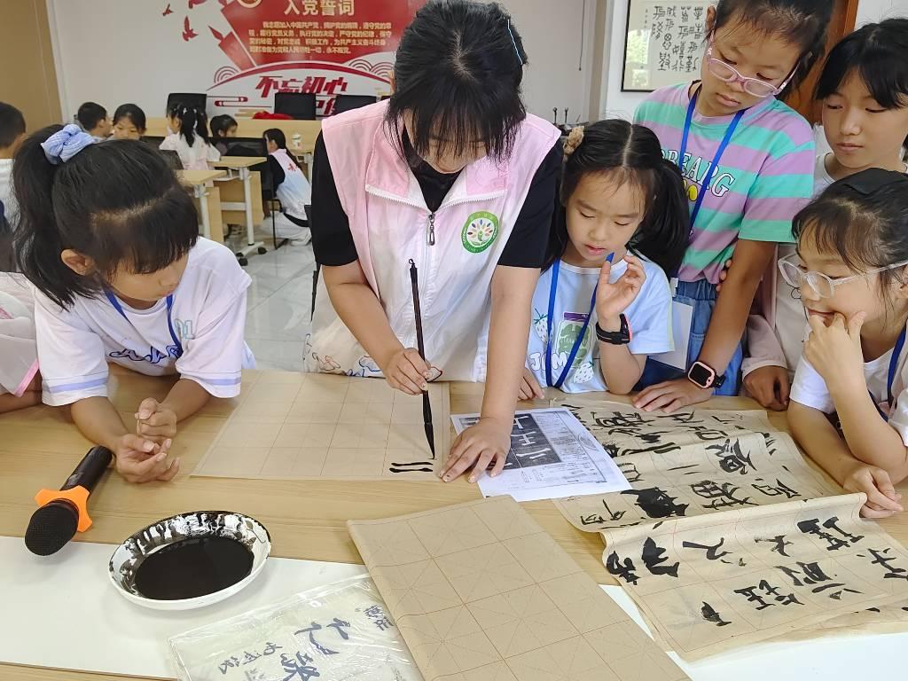 图为志愿者利用自身优势，向小朋友们提供书法的课程，小朋友们在认真的观摩。中国大学生网报通讯员 赵梓茗 摄