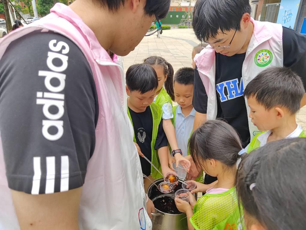 图为志愿者提着盛酸梅汤的桶供小朋友们打酸梅汤，给社区周围的工作人员送清凉。中国大学生网报通讯员 赵梓茗 摄