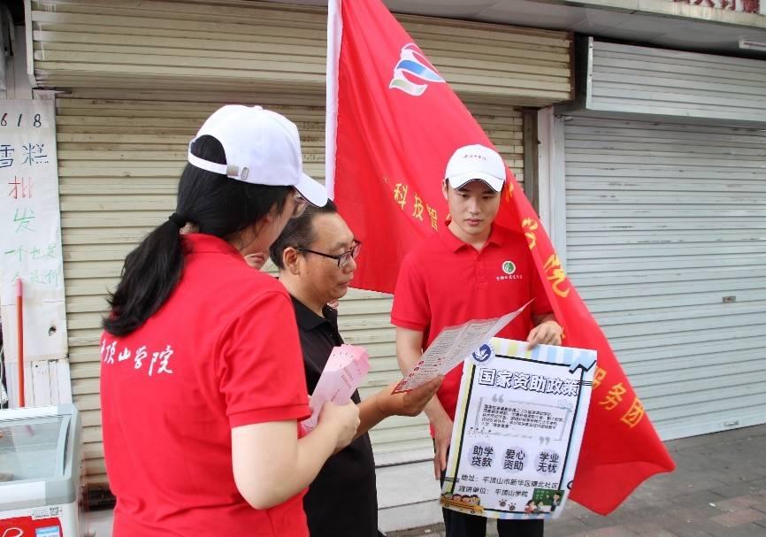 图为志愿者为居民分发国家资助政策手册，详细解读手册内容。 刘欣 供图