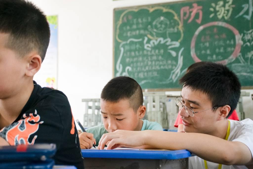 队员辅导学生写作业，给学生讲解习题，帮助学生掌握学习方法