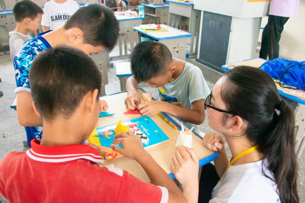 “十二生肖”课堂上，队员指导学生折兔子，学生将所学知识化为手工操作，感受合作的乐趣