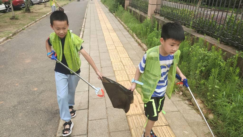 两位小朋友兴致勃勃的打扫街道上的垃圾。