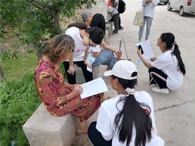 图为实践队员对群众进行问卷调查，统计群众对绿色发展道路了解的情况，并用所学的知识进行讲解。大学生网报网通讯员 金姿含 摄