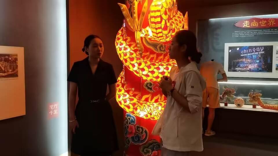 图为团队成员向铜梁区博物馆工作人员了解馆中龙灯龙舞展品。铜梁博物馆中珍藏有许多铜梁龙舞传承人与手艺人制作的精美的龙灯展品。