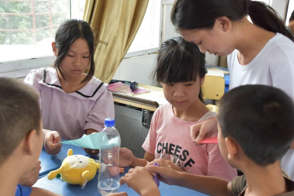 图为科学小实验课上，志愿者指导学生完成实验，学生对于实验非常感兴趣，积极性都非常高。大学生网报通讯员 王曼昕供图