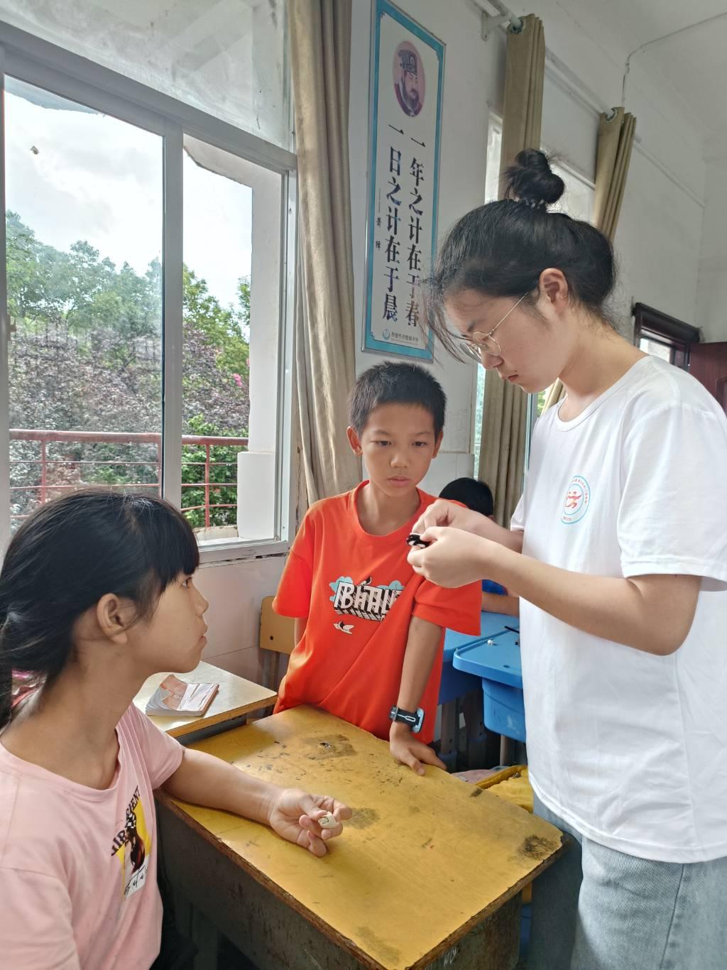 图为手工课上志愿者教学生用扭扭棒制作蜘蛛，学生们第一次制作这样的东西，都感到很新奇，所以每个同学都积极的参与了进来。大学生网报通讯员 王曼昕供图