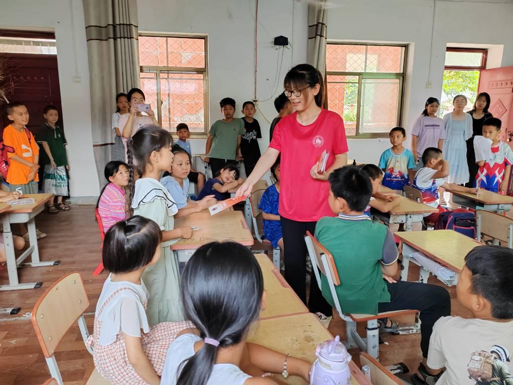 图为志愿者在河南省开封市兰考县程场小学发放消防科普知识宣传页。