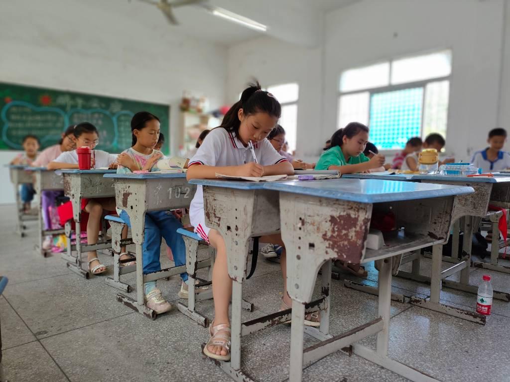 学生们在志愿者的安排下静静且认真地完成老师布置的暑期作业。