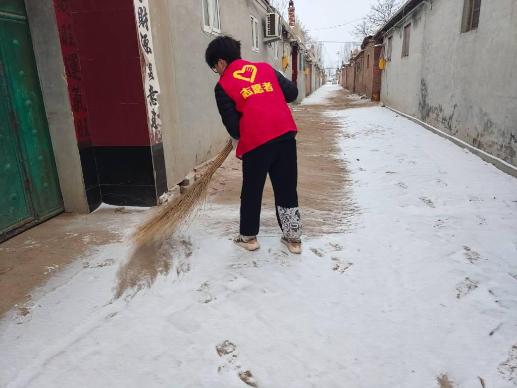 图为“践行时代信仰，传承精神火炬”实践队队员在扫雪。