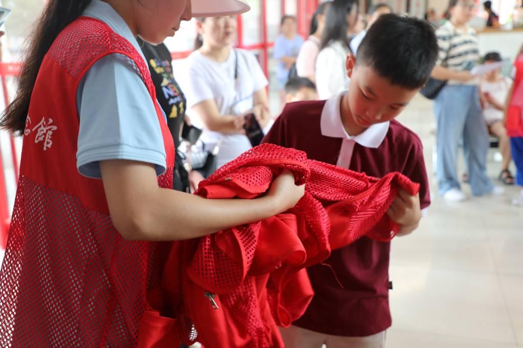 志愿接待员为到达湖南雷锋纪念馆游客中心的同学们有序发放红马甲。