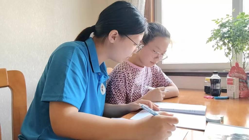 图为志愿者丁晓阳正在辅导军人子女功课。