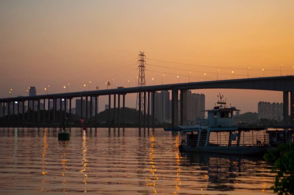 夕阳映照桥上灯光倒影，水面上瑰丽交融，画面宛如仙境，美不胜收。