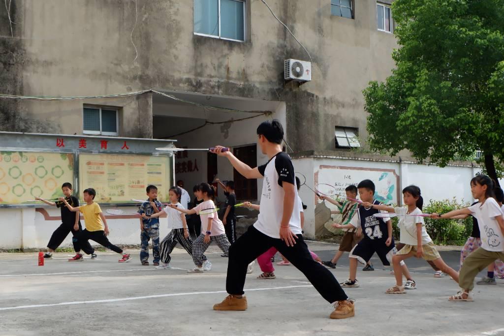 图为老师在教孩子们羽毛球的发球姿势。中国青年网通讯员 李鑫 摄