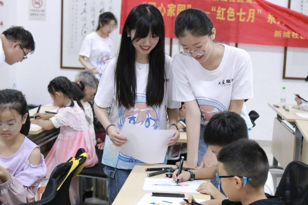 图为苏州城市学院大爱微行团队成员与小朋友交流作品。