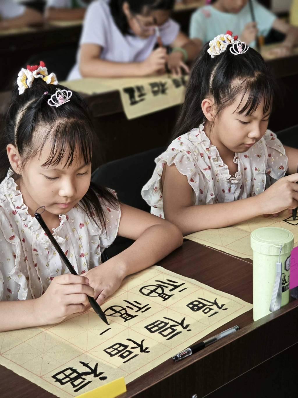 图为课堂上双胞胎姐妹在志愿者队员的指导下书写”福“字。