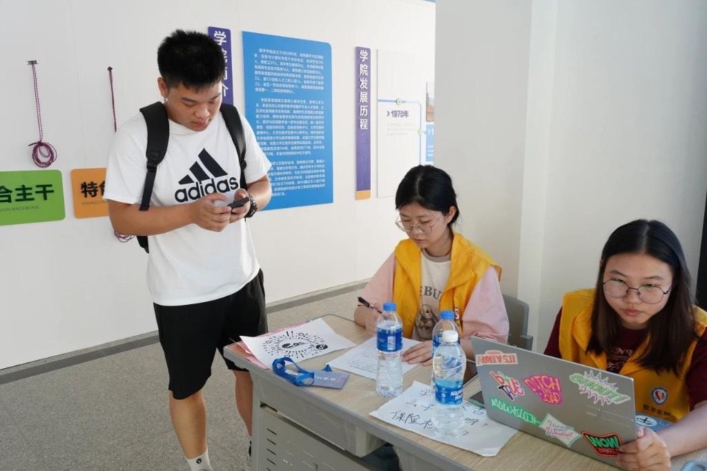 志愿者认真服务刚刚来到学校报道的“小萌新”，为新生提供温暖服务