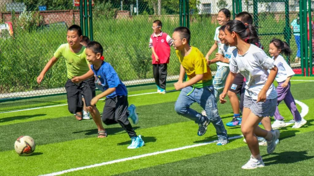 图为“春蕾”爱心支教服务团成员带领小朋友们在绿茵场上踢足球，在正式踢足球的前一天，“春蕾”爱心支教服务团成员给小朋友们上了一次关于足球的理论课，讲解了足球的专业知识以及保护措施。