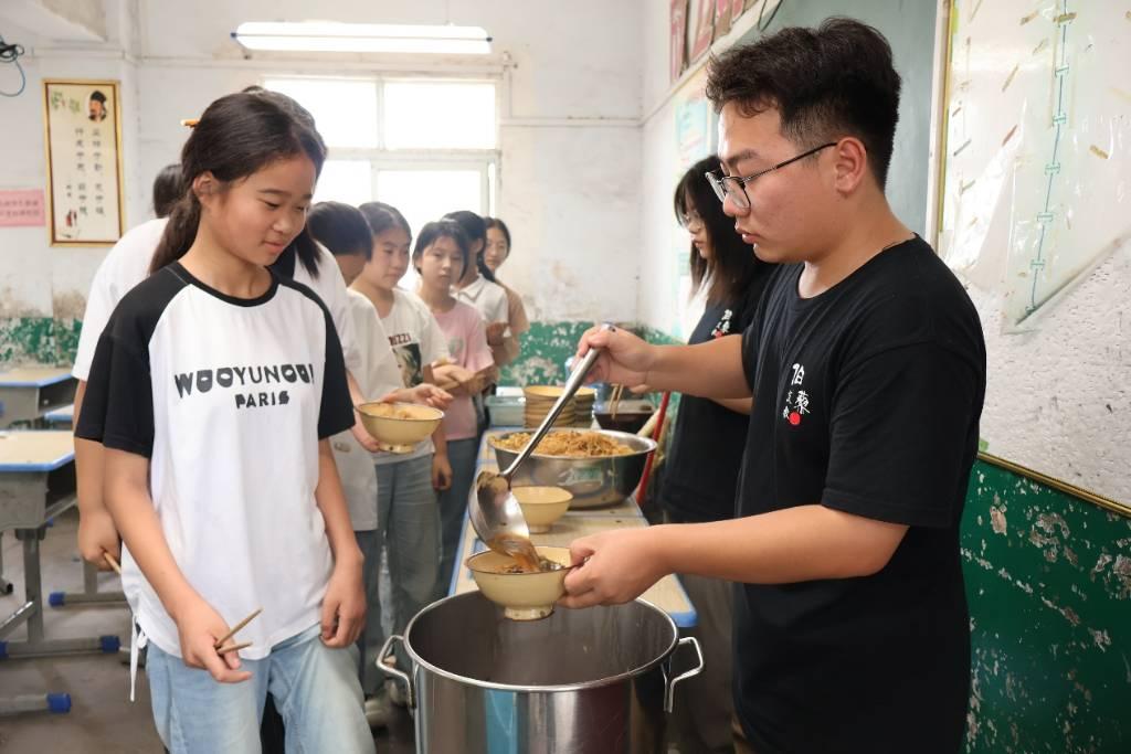 图为支教团成员在为自己班级的学生们乘取午餐。通讯员 安瑶 供图