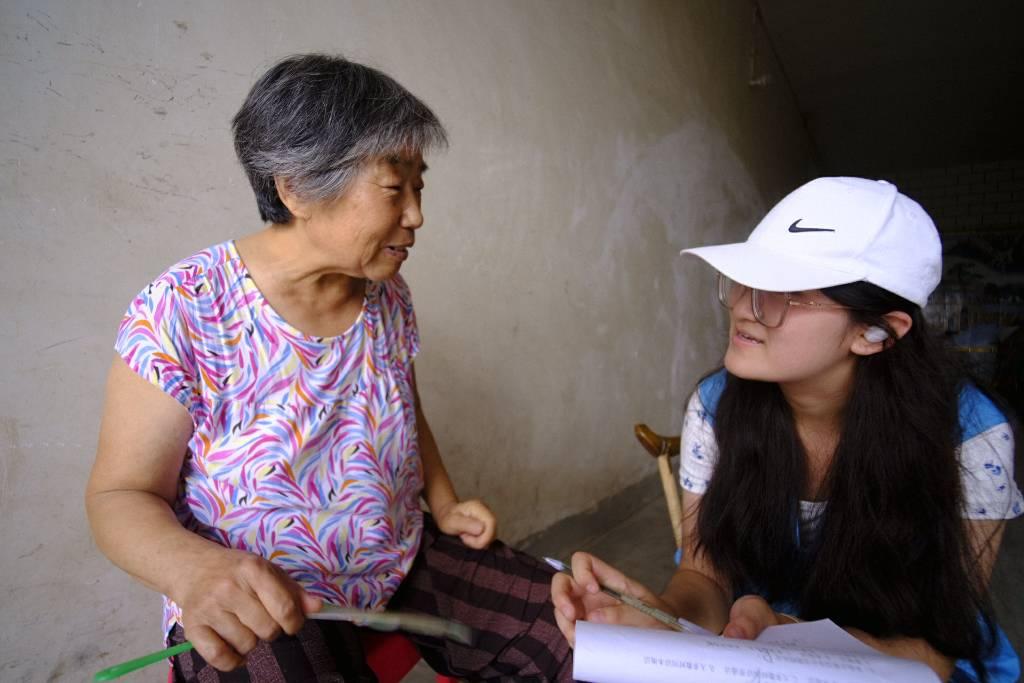 图为团队成员在吕村进行爱国主义教育调研，聆听老人讲述当地爱国故事。