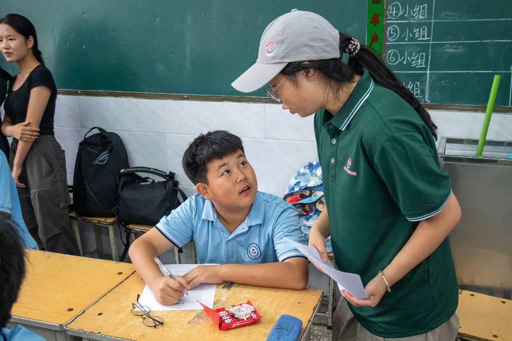 图为团队成员在学校向青少年调查普通话应用情况及学习普通话难点。